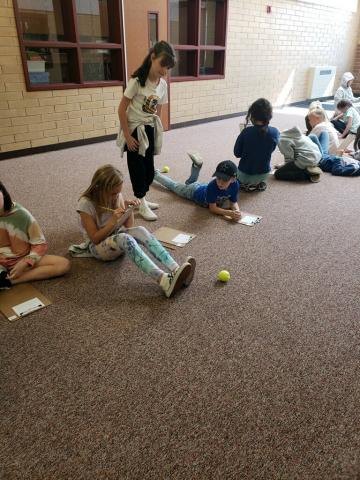 Students testing out energy with a tennis ball.